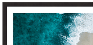 Top-down view of ocean waves crashing onto a beach with a black frame.