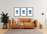 Living room with orange sofa and three framed Eiffel Tower photos on the wall.